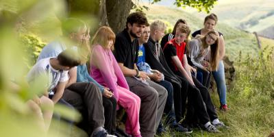 Group of young people on a YHA trip sitting in the countryside