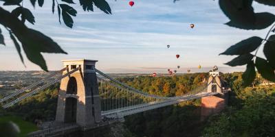 Hot air balloons flying over a suspension bridge