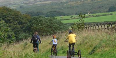 Adult and two children cycling through the countryside