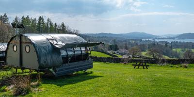 Glamping Landpod on a grass field overlooking a lake