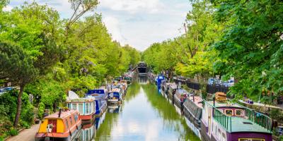 Canal with rows of canal boats surrounded by green trees