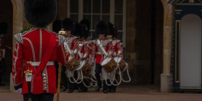 Guardians wearing tall black hats and red coats outside Buckingham Palace