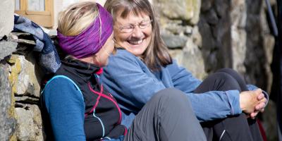 Two women sat down laughing against stone wall at YHA Black Sail