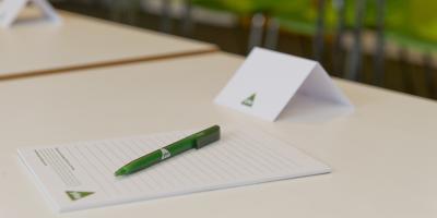 White notepad and namecard sitting on a table with a green pen