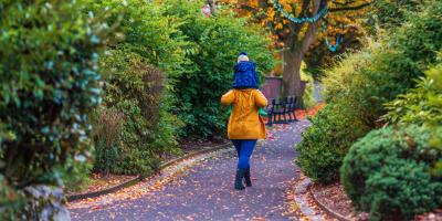 Parent walking a park with a child on their shoulders