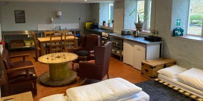 Studio room with futon beds, armchairs and kitchen cupboards