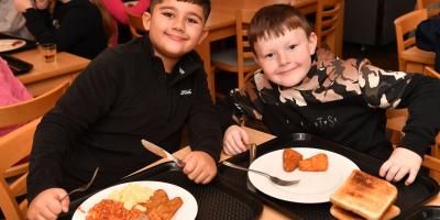 Two smiling boys eating a cooked breakfast