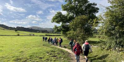 Walkers walking across fields in Hartington on a sunny day