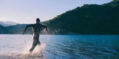 Swimmer wearing a wetsuit wading into a lake