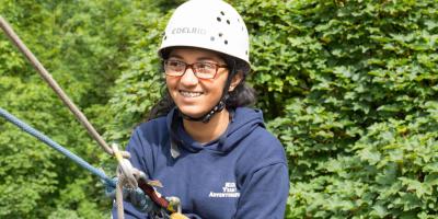 Abseiling teenager smiling while wearing a safety hard hard