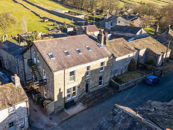 Stone hostel building with houses and green rolling hills in the background